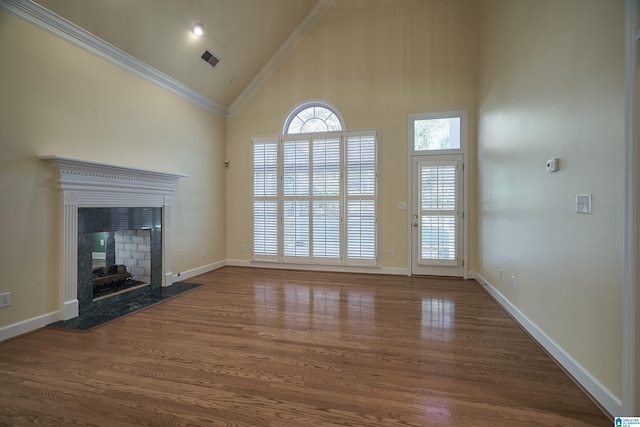 unfurnished living room featuring crown molding, a high end fireplace, dark wood-type flooring, and high vaulted ceiling