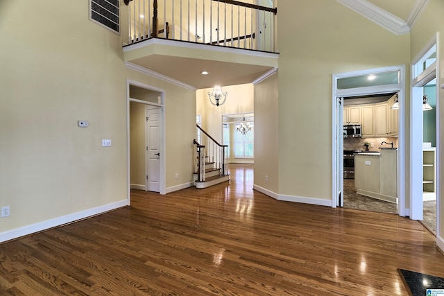 unfurnished living room featuring ornamental molding, a towering ceiling, and dark wood-type flooring