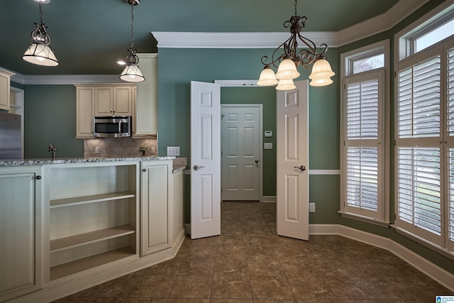 kitchen with an inviting chandelier, light stone counters, crown molding, decorative light fixtures, and appliances with stainless steel finishes