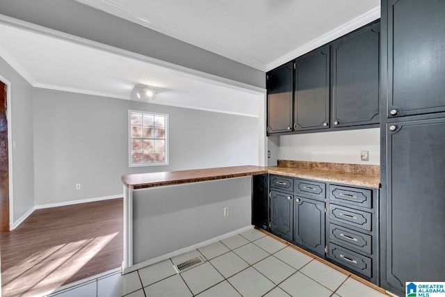 kitchen featuring crown molding, built in desk, and light wood-type flooring