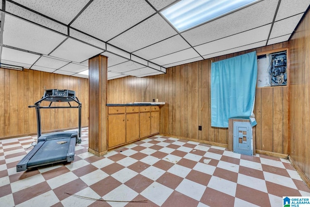 interior space with a drop ceiling and wood walls