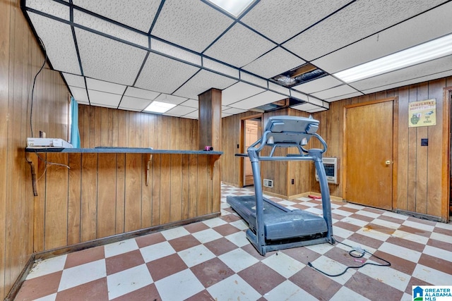 workout room featuring a paneled ceiling and wooden walls