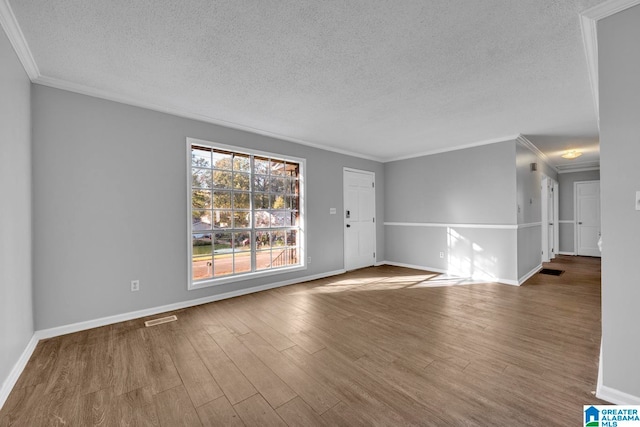 spare room featuring crown molding, hardwood / wood-style floors, and a textured ceiling