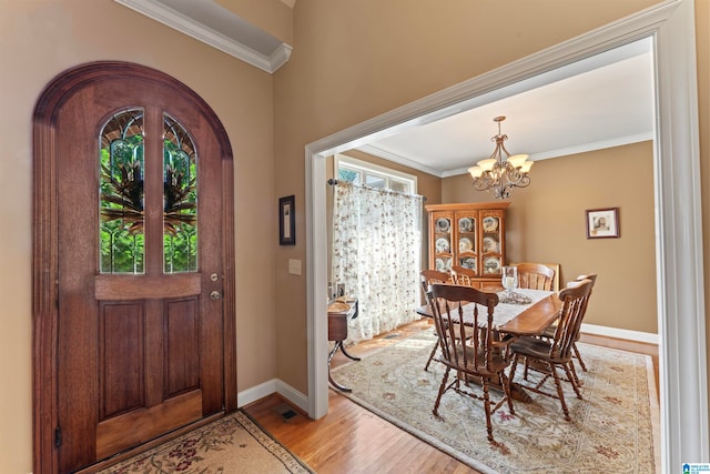 entrance foyer featuring an inviting chandelier, ornamental molding, and light wood-type flooring