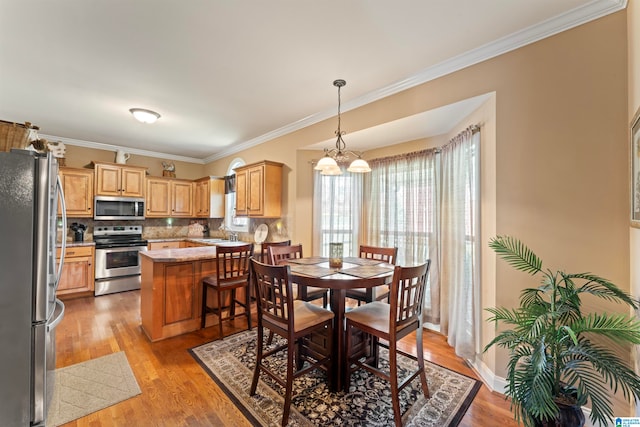 dining room featuring sink, a notable chandelier, light hardwood / wood-style flooring, and ornamental molding