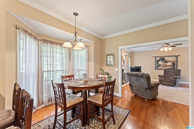 dining space with crown molding, wood-type flooring, and ceiling fan with notable chandelier