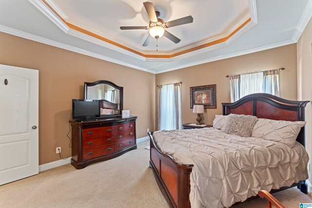 carpeted bedroom featuring crown molding, a tray ceiling, and ceiling fan