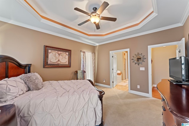 bedroom with a raised ceiling, ensuite bathroom, ornamental molding, and ceiling fan