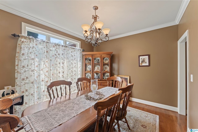 dining area with hardwood / wood-style floors, ornamental molding, and a chandelier