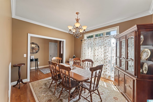 dining space with hardwood / wood-style flooring, crown molding, and a notable chandelier