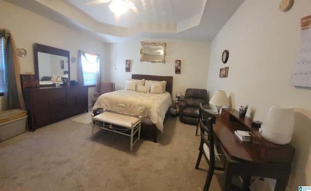 carpeted bedroom with a raised ceiling and ceiling fan