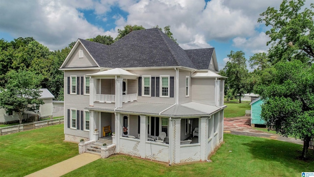 back of property with covered porch, a balcony, and a yard