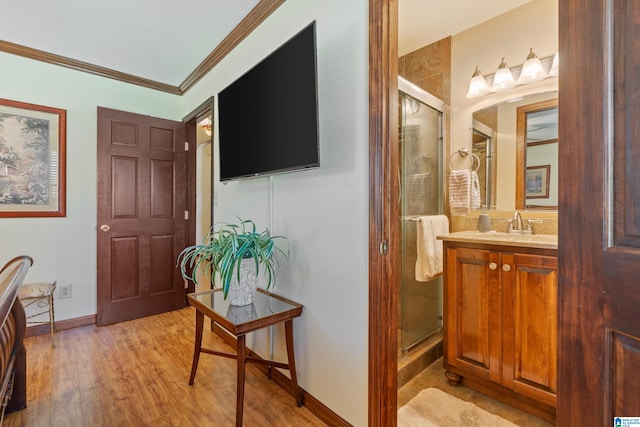 hall with a textured ceiling, light wood-type flooring, ornamental molding, and sink