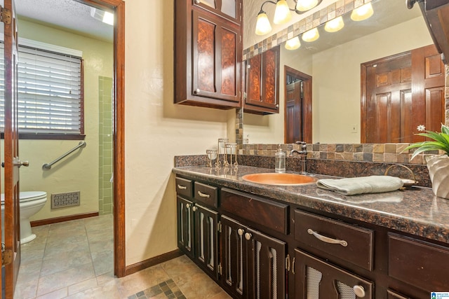 bathroom with tile patterned flooring, a textured ceiling, vanity, and toilet