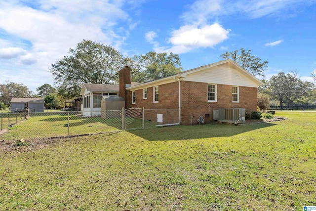 back of property featuring central air condition unit and a yard