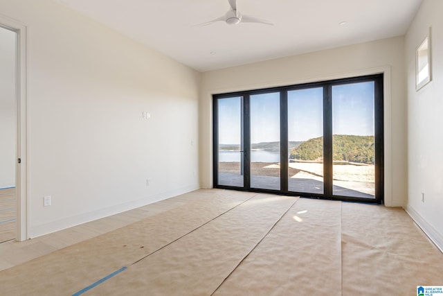 empty room featuring a water view, ceiling fan, and light hardwood / wood-style floors