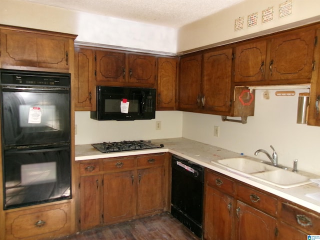 kitchen featuring a textured ceiling, sink, black appliances, and dark hardwood / wood-style floors