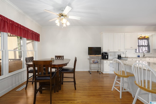 dining room featuring sink, ceiling fan, crown molding, and dark wood-type flooring