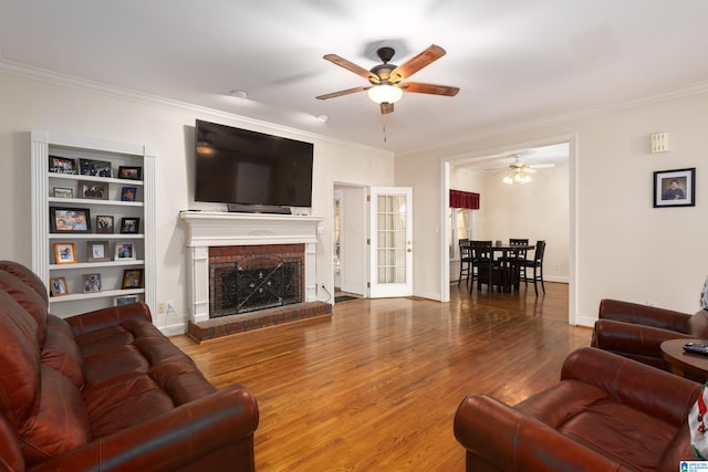 living room featuring crown molding, a fireplace, ceiling fan, and hardwood / wood-style flooring