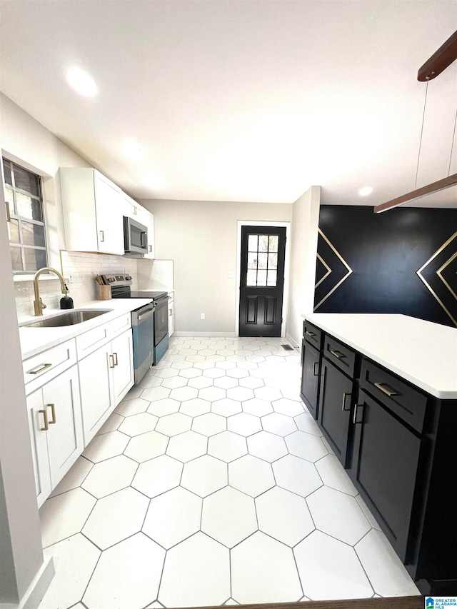 kitchen with backsplash, stainless steel appliances, sink, white cabinetry, and hanging light fixtures