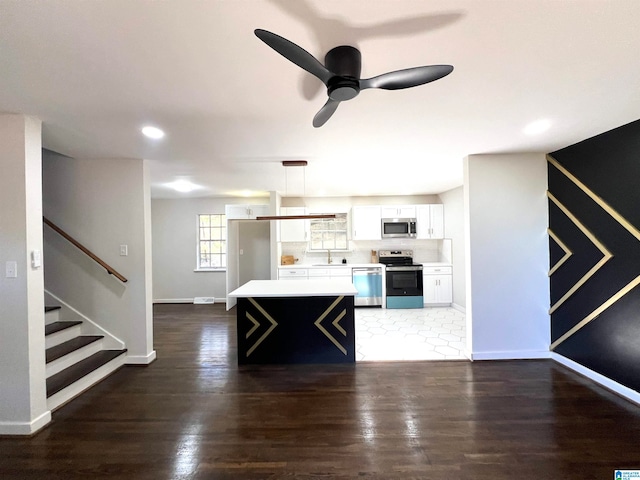 kitchen featuring dark wood-type flooring, white cabinets, sink, appliances with stainless steel finishes, and decorative light fixtures