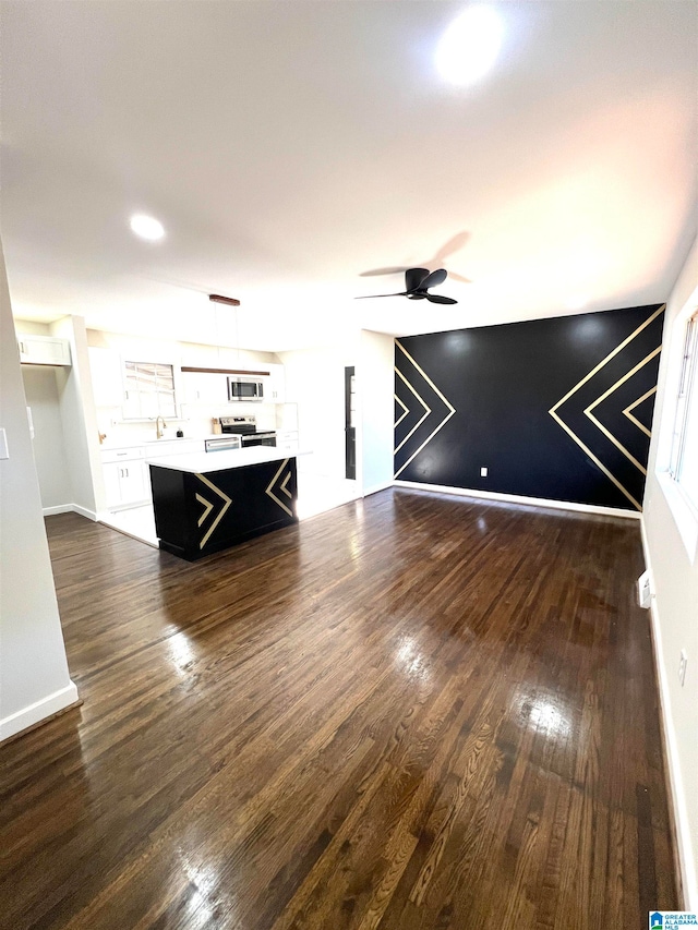 unfurnished living room featuring ceiling fan and dark hardwood / wood-style floors