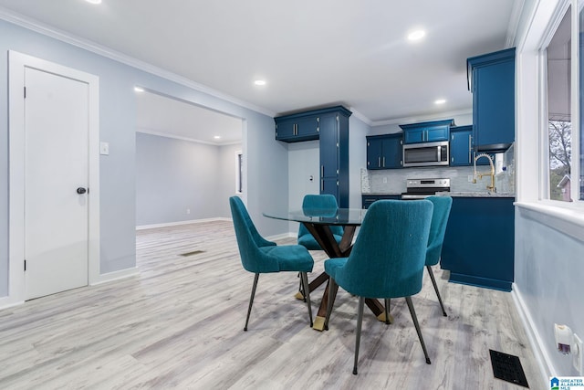 dining space with sink, light hardwood / wood-style flooring, and ornamental molding