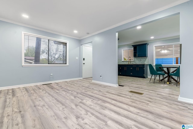 unfurnished living room featuring light hardwood / wood-style flooring, ornamental molding, and sink