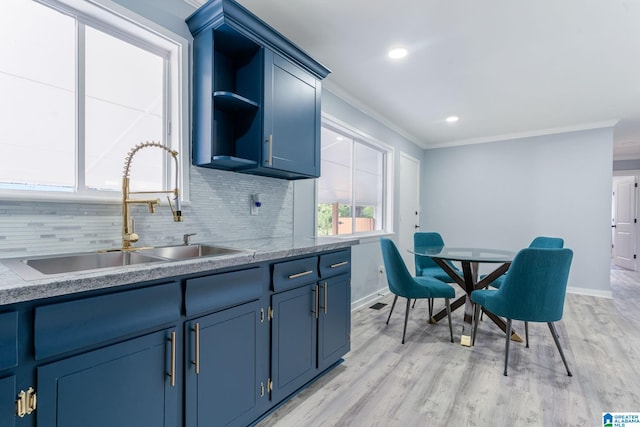 kitchen with light wood-type flooring, backsplash, ornamental molding, blue cabinets, and sink