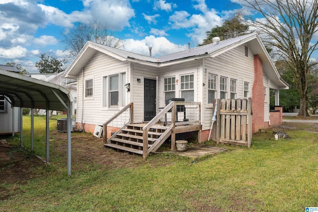 rear view of house featuring central AC, a carport, and a lawn