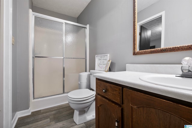 bathroom with vanity, toilet, a textured ceiling, walk in shower, and wood-type flooring