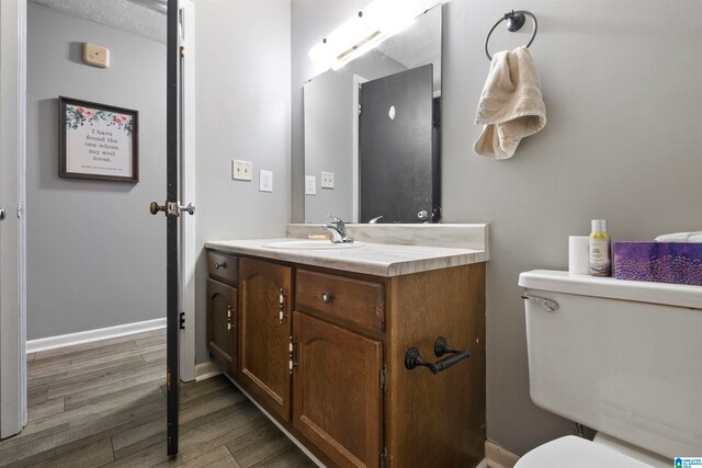 bathroom featuring a textured ceiling, vanity, hardwood / wood-style flooring, and toilet