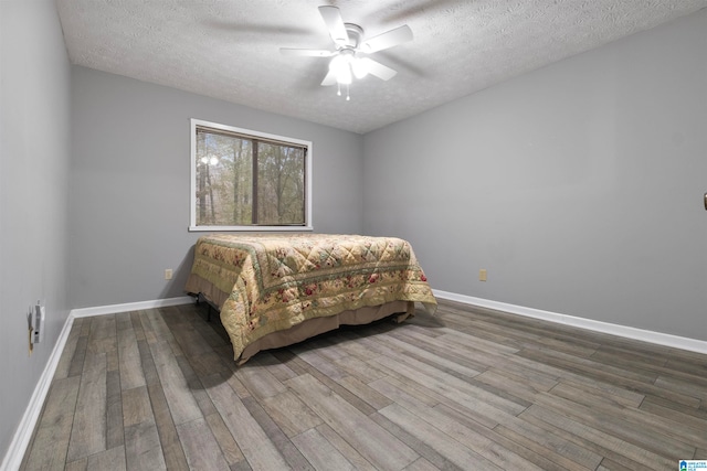 bedroom featuring ceiling fan, hardwood / wood-style floors, and a textured ceiling