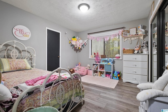 bedroom featuring a textured ceiling and light hardwood / wood-style flooring