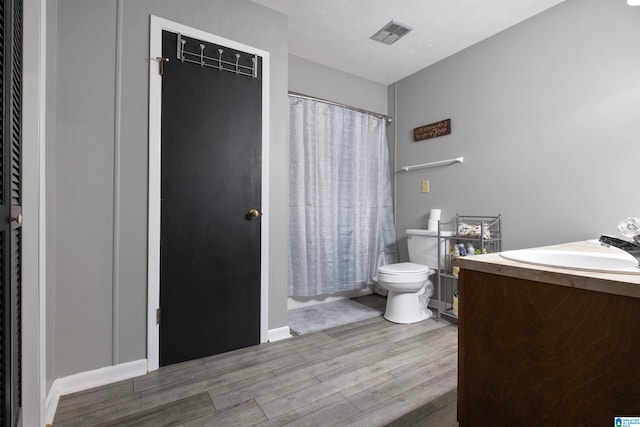 full bathroom with shower / bath combination with curtain, vanity, a textured ceiling, wood-type flooring, and toilet