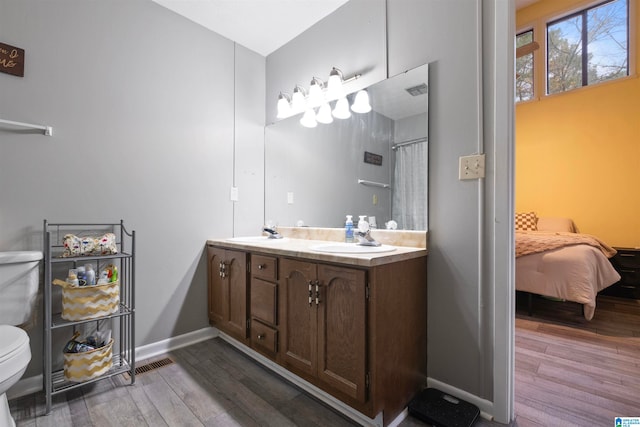 bathroom with hardwood / wood-style floors, vanity, toilet, and walk in shower