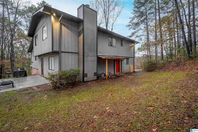 view of side of property with a patio and a lawn