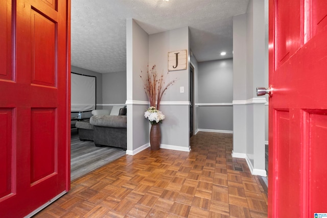 foyer entrance with dark parquet flooring and a textured ceiling