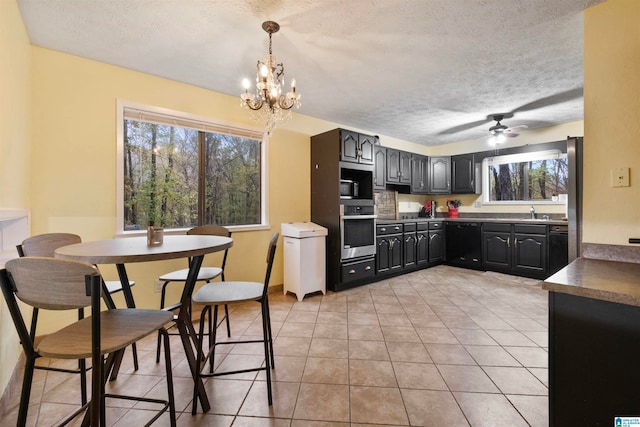 kitchen featuring a textured ceiling, ceiling fan with notable chandelier, and stainless steel appliances