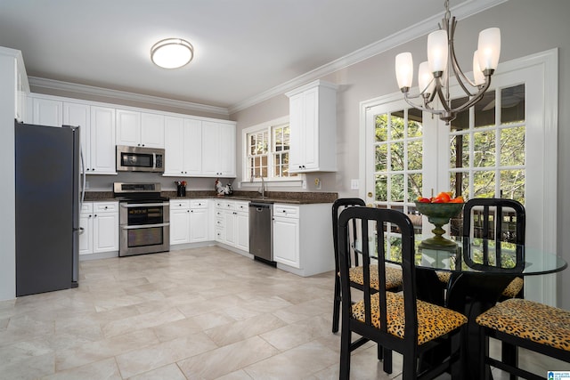 kitchen featuring hanging light fixtures, ornamental molding, appliances with stainless steel finishes, white cabinetry, and a chandelier