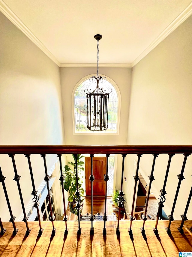 staircase with crown molding, wood-type flooring, and an inviting chandelier