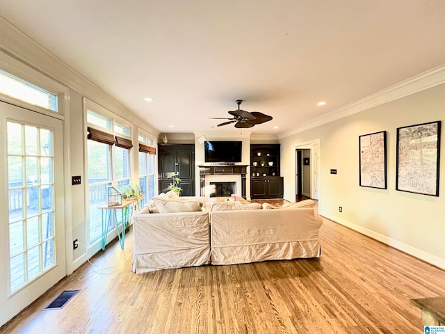 living room featuring light wood-type flooring, ceiling fan, and crown molding