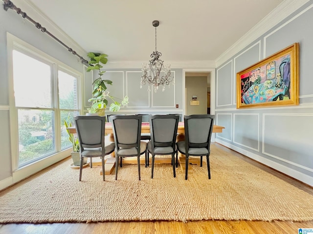 dining area with hardwood / wood-style floors, ornamental molding, a wealth of natural light, and a notable chandelier