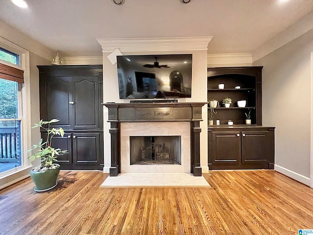 unfurnished living room with light wood-type flooring, crown molding, and a premium fireplace