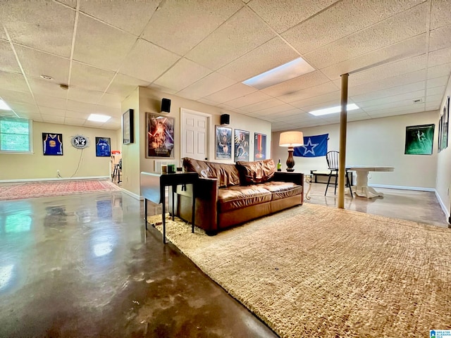 living room with a paneled ceiling and concrete flooring