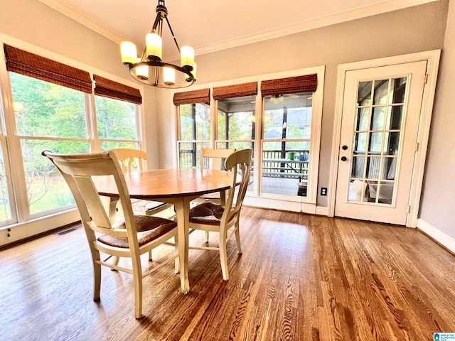 dining area with hardwood / wood-style floors, plenty of natural light, crown molding, and a chandelier