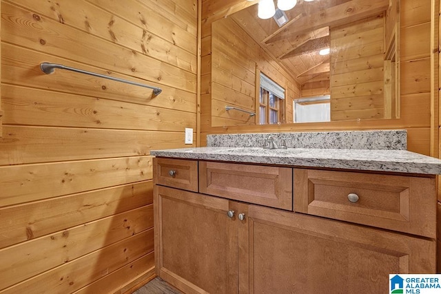 bathroom featuring vanity, vaulted ceiling, and wooden walls