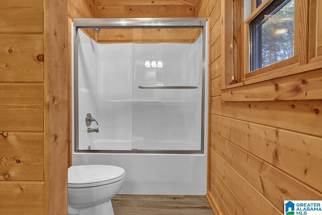 bathroom featuring wood walls, toilet, enclosed tub / shower combo, and wood-type flooring