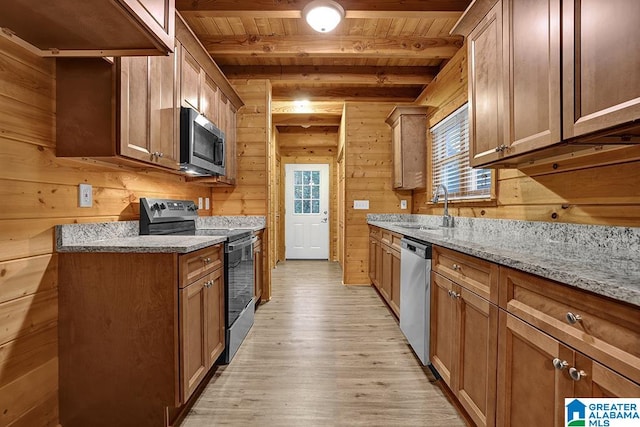 kitchen with wood walls, plenty of natural light, stainless steel appliances, and sink