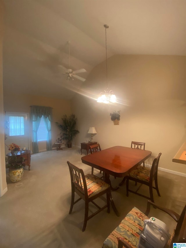 dining area with ceiling fan with notable chandelier, carpet floors, and vaulted ceiling